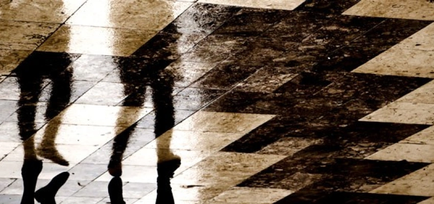 Spiegelung zweier laufenden Personen auf schwarz weiß gemusterten Fliesen