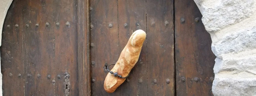 In einer alten Holztür steckt ein Baguette.