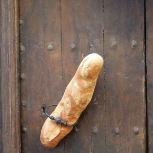 In einer alten Holztür steckt ein Baguette.