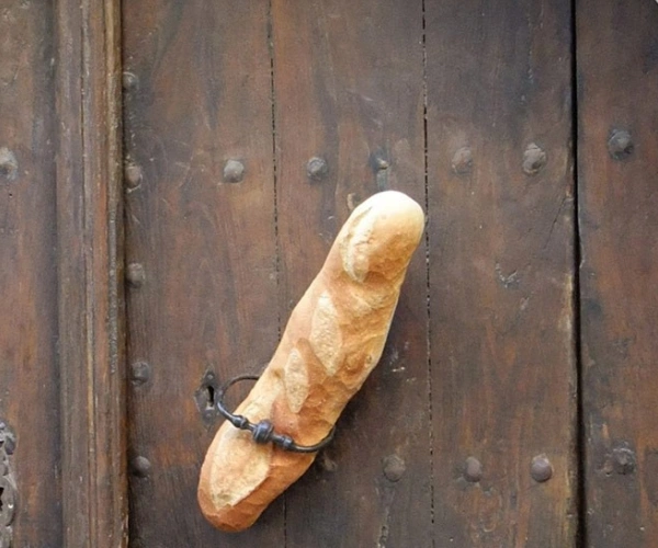In einer alten Holztür steckt ein Baguette.