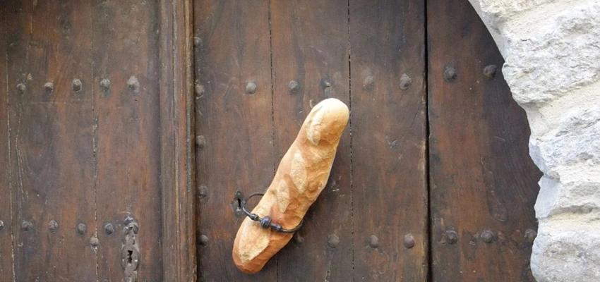 In einer alten Holztür steckt ein Baguette.