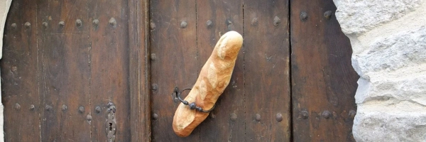 In einer alten Holztür steckt ein Baguette.