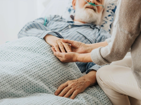Hände eines Mannes auf dem Sterbebett