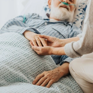 Hände eines Mannes auf dem Sterbebett