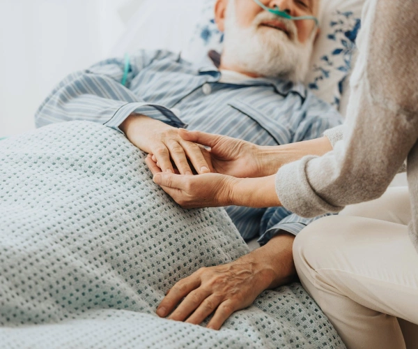 Hände eines Mannes auf dem Sterbebett