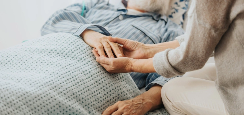 Hände eines Mannes auf dem Sterbebett