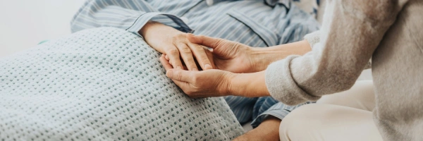 Hände eines Mannes auf dem Sterbebett