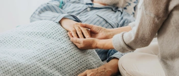 Hände eines Mannes auf dem Sterbebett