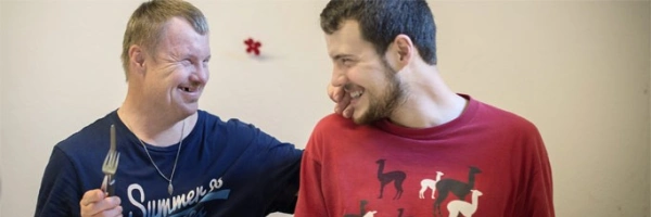 zwei sitzende Menschen grinsen sich herzlich an